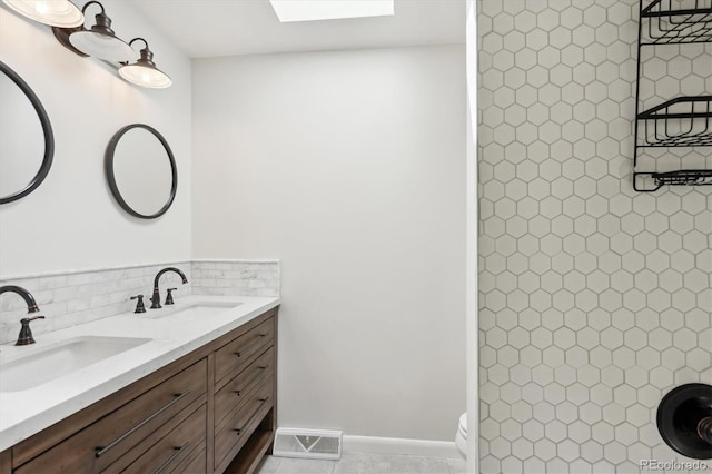 full bath featuring visible vents, a sink, backsplash, and double vanity