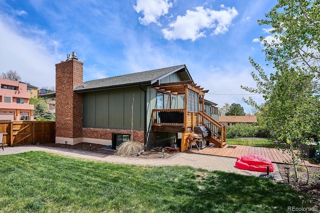 back of house featuring fence, a deck, a chimney, board and batten siding, and a lawn