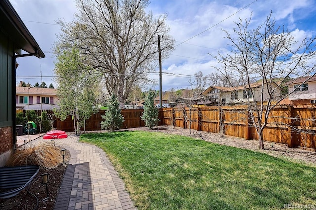 view of yard featuring a residential view, a fenced backyard, and a patio area