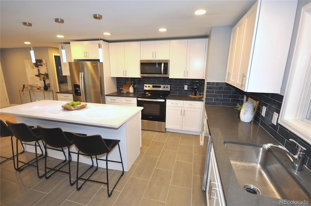 kitchen with stainless steel appliances, white cabinetry, and decorative light fixtures