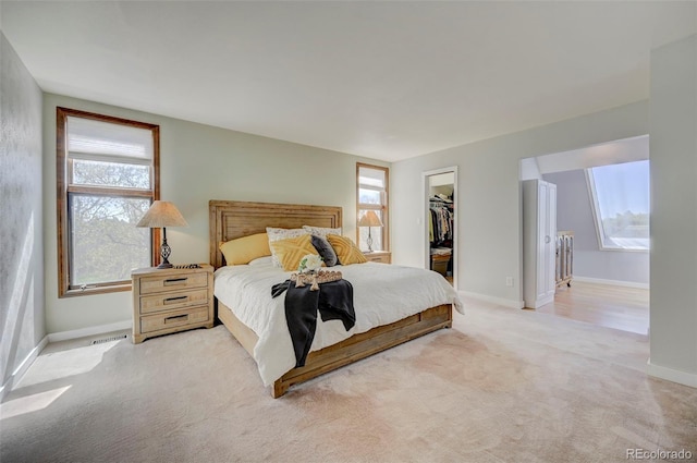 18045 Sunburst Dr, Monument, CO 80132 - bedroom featuring light carpet, a walk in closet, baseboards, a closet, and ensuite bath