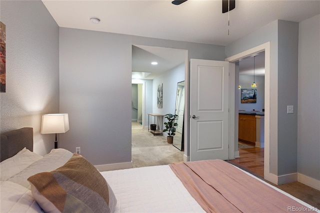 bedroom featuring baseboards, light colored carpet, and a ceiling fan