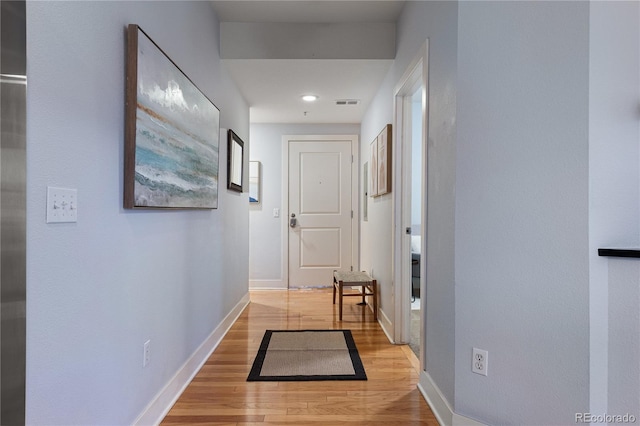 hall with visible vents, light wood-style flooring, and baseboards