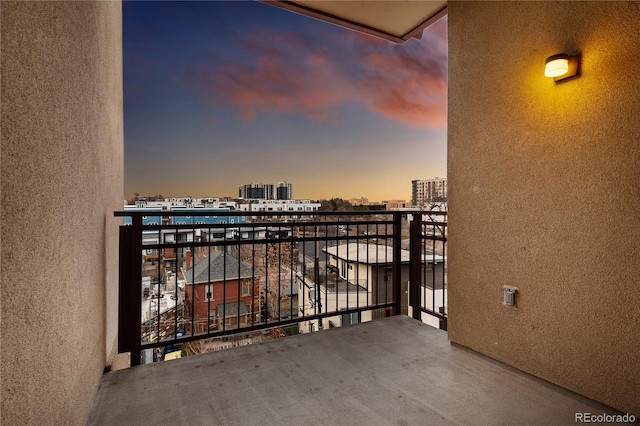 balcony at dusk featuring a view of city