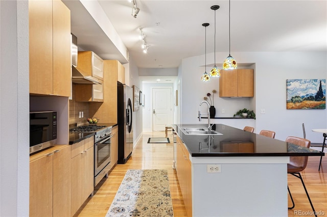 kitchen with a kitchen breakfast bar, dark countertops, a center island with sink, appliances with stainless steel finishes, and a sink