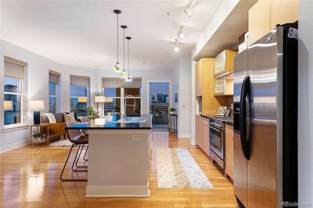 2240 N Clay St Unit 501, Denver, CO 80211 - kitchen featuring stainless steel appliances, dark countertops, an island with sink, light wood-style flooring, and baseboards