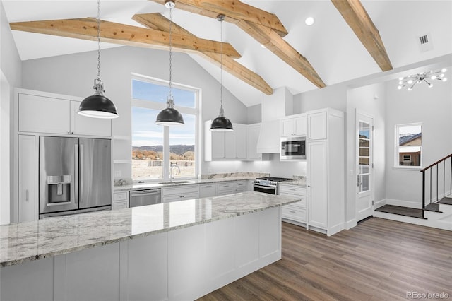 kitchen with appliances with stainless steel finishes, beamed ceiling, light stone counters, and white cabinetry