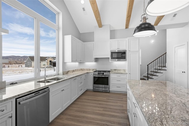 kitchen featuring appliances with stainless steel finishes, decorative light fixtures, white cabinetry, sink, and beam ceiling