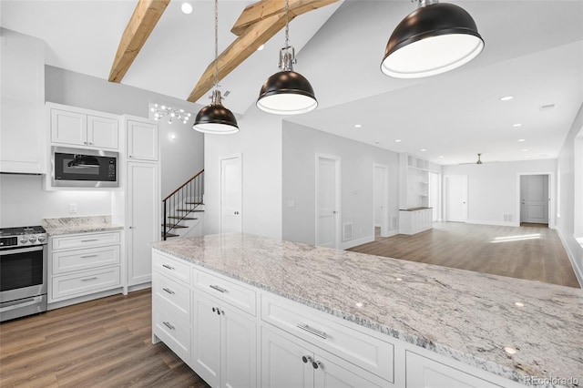 kitchen featuring built in microwave, hanging light fixtures, white cabinets, and stainless steel gas range oven