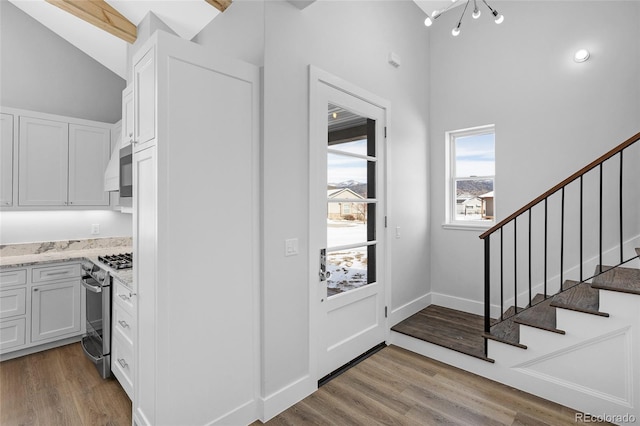 foyer entrance with light hardwood / wood-style floors and lofted ceiling with beams