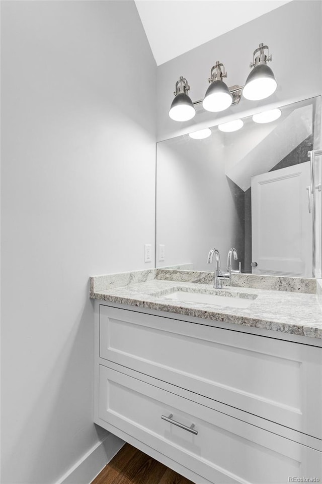 bathroom with lofted ceiling, vanity, and hardwood / wood-style flooring