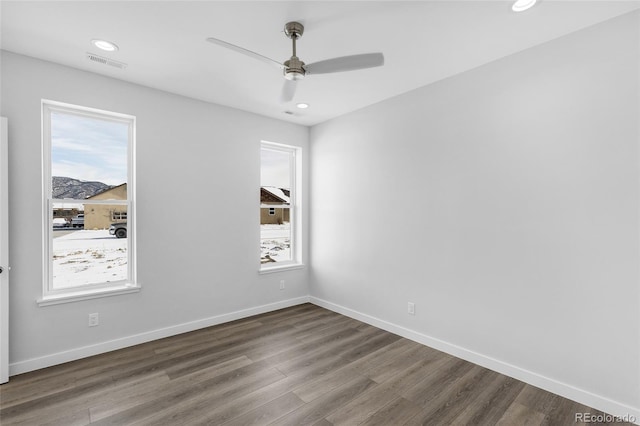 empty room with ceiling fan, plenty of natural light, and hardwood / wood-style flooring