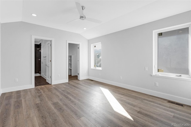 unfurnished bedroom with ceiling fan, a walk in closet, vaulted ceiling, and hardwood / wood-style floors