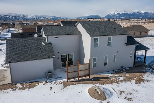 snow covered house featuring cooling unit and a mountain view