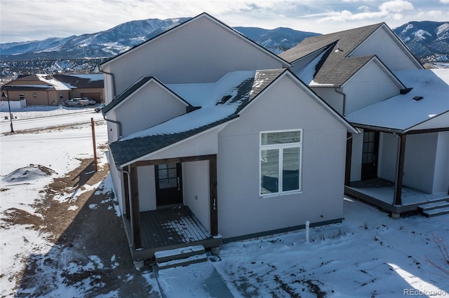 view of front of house featuring a shingled roof, a mountain view, and stucco siding