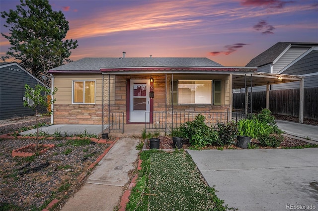 1910 S King St, Denver, CO 80219 - view of front of property featuring stone siding, a porch, a shingled roof, and an attached carport
