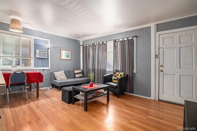 1910 S King St, Denver, CO 80219 - living room featuring a textured wall, light wood finished floors, crown molding, and an AC wall unit