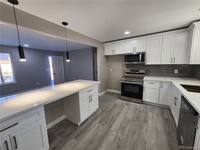 kitchen featuring appliances with stainless steel finishes, pendant lighting, backsplash, and white cabinets