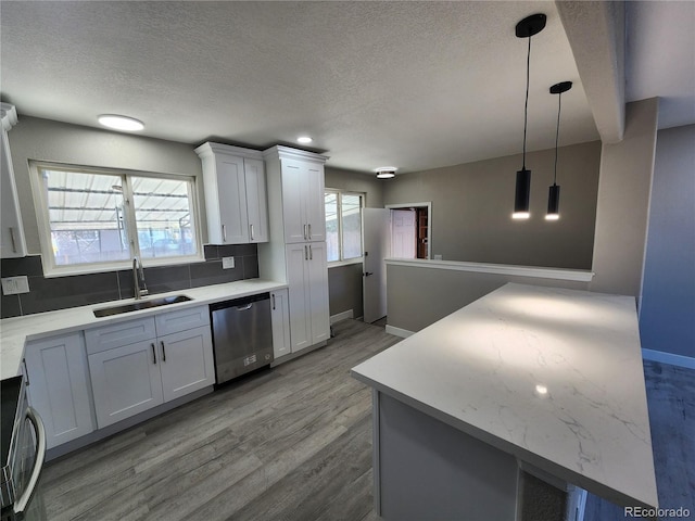 kitchen featuring white cabinetry, dishwasher, hanging light fixtures, and sink