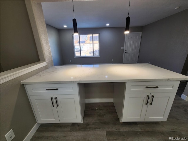 kitchen with light stone countertops, pendant lighting, built in desk, white cabinetry, and kitchen peninsula