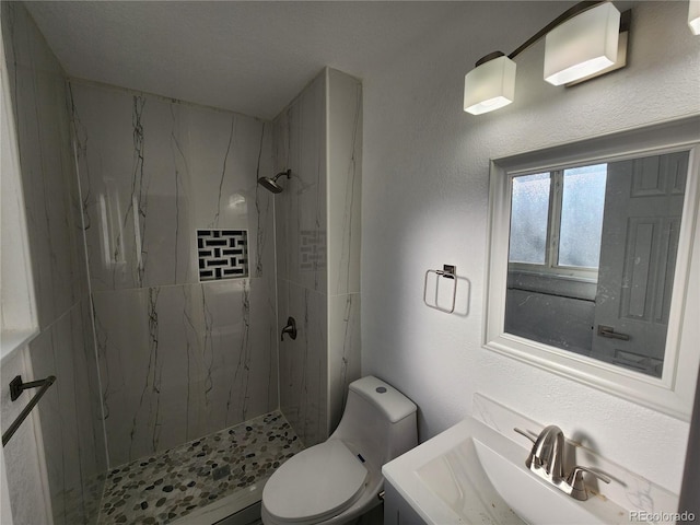 bathroom with toilet, vanity, and a tile shower