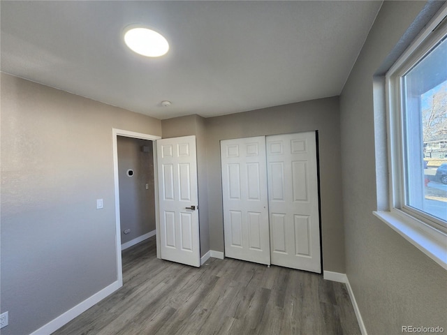 unfurnished bedroom featuring a closet, multiple windows, and light hardwood / wood-style flooring