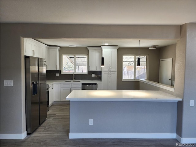 kitchen featuring sink, white cabinetry, decorative light fixtures, kitchen peninsula, and stainless steel appliances