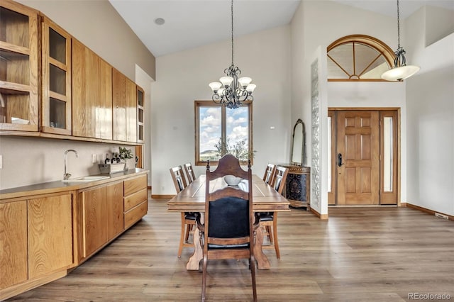 15125 Spring Valley Rd, Larkspur, CO 80118 - dining room with high vaulted ceiling, light wood-style flooring, a chandelier, and baseboards