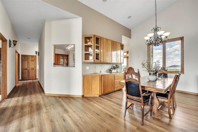 15125 Spring Valley Rd, Larkspur, CO 80118 - dining space featuring light wood finished floors, baseboards, a chandelier, and a towering ceiling
