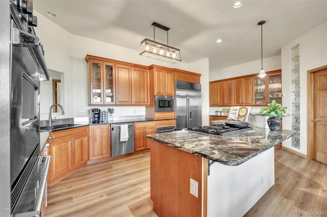 15125 Spring Valley Rd, Larkspur, CO 80118 - kitchen with built in appliances, a sink, light wood-style floors, dark stone counters, and brown cabinetry