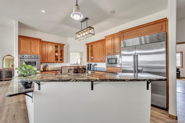 15125 Spring Valley Rd, Larkspur, CO 80118 - kitchen with built in appliances, brown cabinetry, light wood-style flooring, a breakfast bar area, and recessed lighting