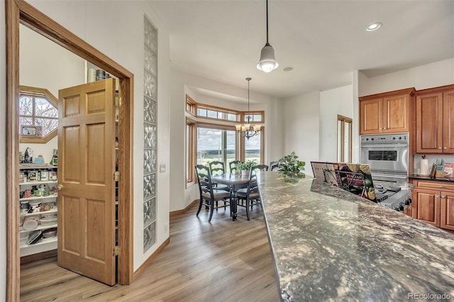 15125 Spring Valley Rd, Larkspur, CO 80118 - kitchen with stainless steel double oven, plenty of natural light, light wood-style floors, decorative light fixtures, and recessed lighting