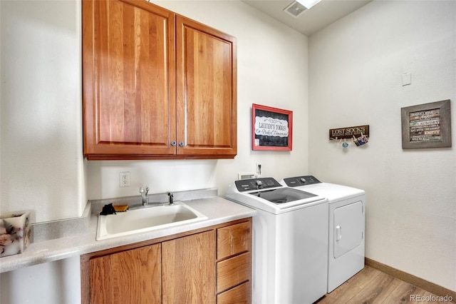 15125 Spring Valley Rd, Larkspur, CO 80118 - washroom featuring cabinet space, independent washer and dryer, light wood-style flooring, and baseboards