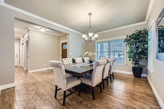 dining room with hardwood / wood-style flooring, ornamental molding, and a chandelier