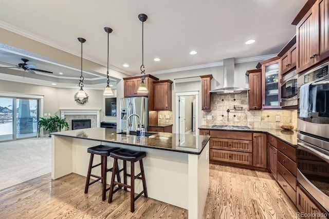 kitchen featuring appliances with stainless steel finishes, decorative light fixtures, backsplash, a kitchen bar, and wall chimney exhaust hood