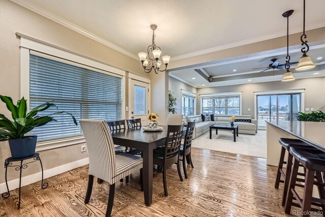 dining space featuring hardwood / wood-style flooring, crown molding, a raised ceiling, and a notable chandelier