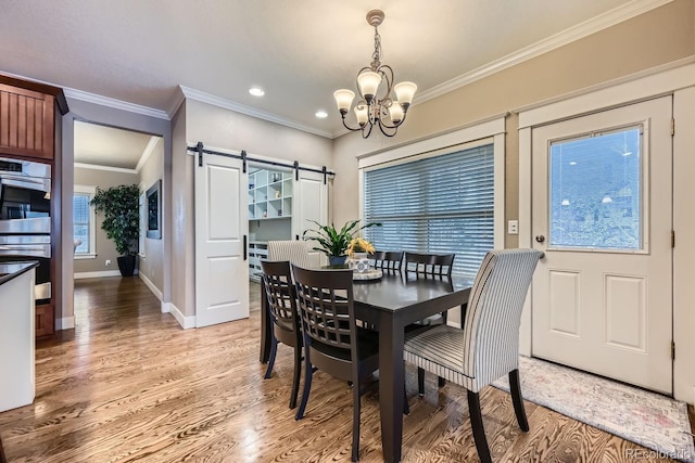 dining room with ornamental molding, a barn door, a chandelier, and hardwood / wood-style floors