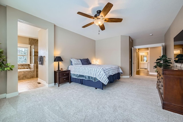 bedroom with ceiling fan, light colored carpet, and ensuite bath