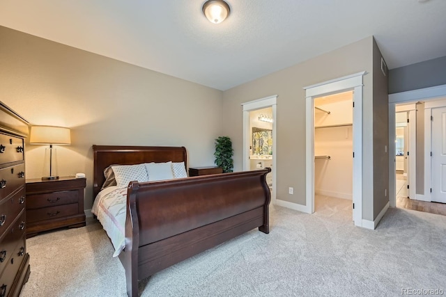 bedroom with a walk in closet, light carpet, connected bathroom, and a closet