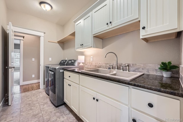 clothes washing area with sink, light tile patterned floors, cabinets, and independent washer and dryer