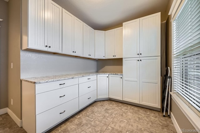 kitchen featuring white cabinets and light stone counters