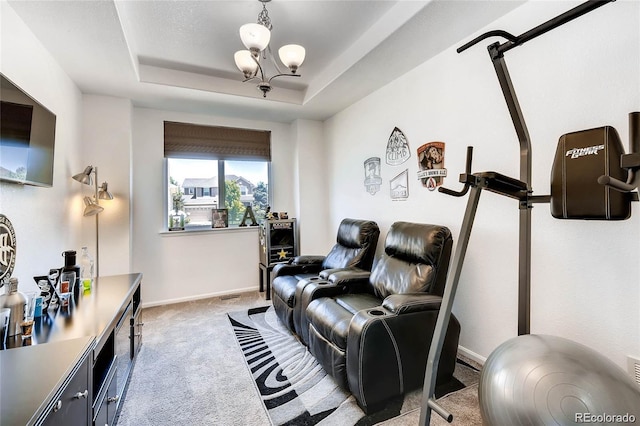 carpeted cinema room with a tray ceiling and an inviting chandelier