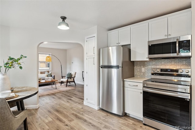 kitchen featuring decorative backsplash, light hardwood / wood-style flooring, white cabinets, and appliances with stainless steel finishes