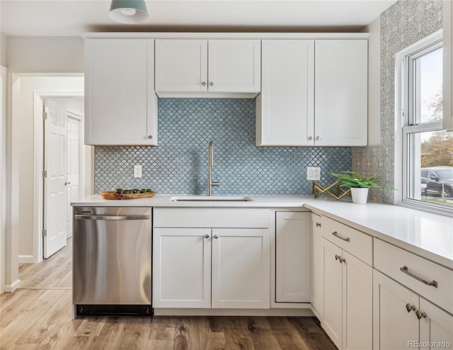 kitchen featuring dishwasher, backsplash, sink, light wood-type flooring, and white cabinetry