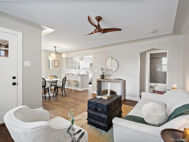 living area with ceiling fan, baseboards, and wood finished floors