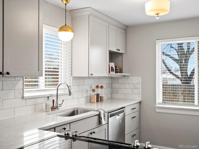 kitchen with pendant lighting, open shelves, tasteful backsplash, stainless steel dishwasher, and a sink