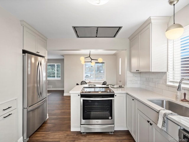 kitchen with light countertops, appliances with stainless steel finishes, a sink, and tasteful backsplash