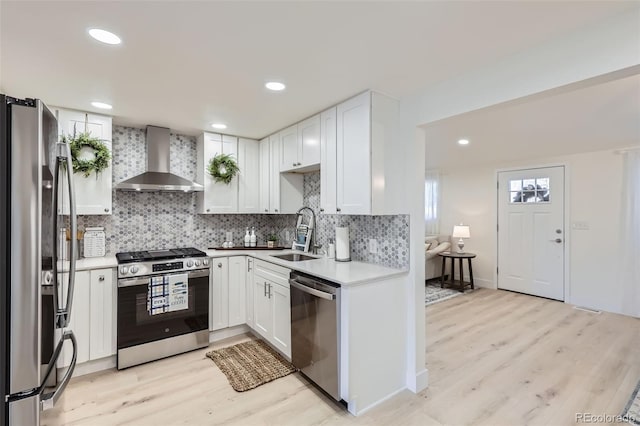 8985 Lander St, Westminster, CO 80031 - kitchen with stainless steel appliances, wall chimney exhaust hood, a sink, light wood finished floors, and backsplash