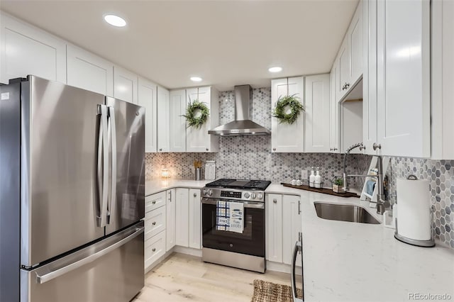 8985 Lander St, Westminster, CO 80031 - kitchen with appliances with stainless steel finishes, wall chimney exhaust hood, a sink, white cabinetry, and recessed lighting