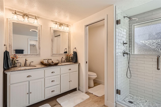 8985 Lander St, Westminster, CO 80031 - full bathroom featuring a shower stall, wood finished floors, double vanity, and toilet